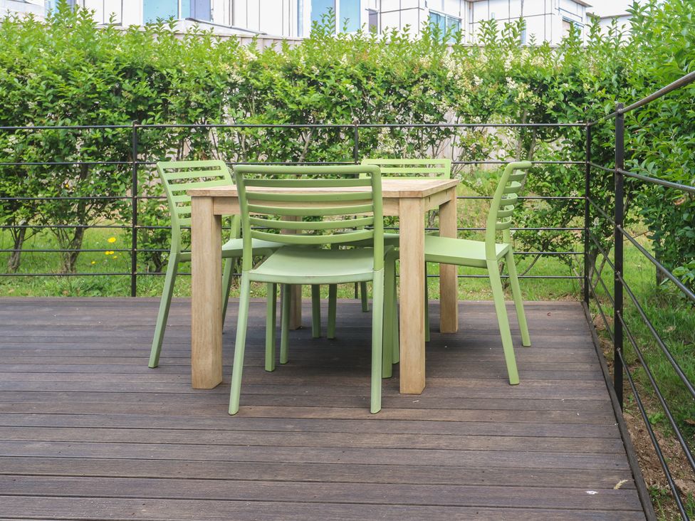 An outdoor seating area with a wooden table and green chairs at Una, Lodge 70 Carbis Bay