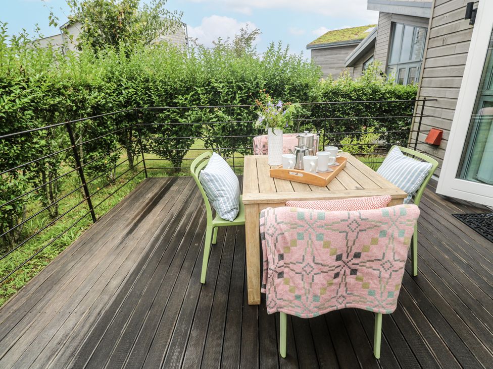 A dining area with a table and chairs on a deck at Una, Lodge 70 Carbis Bay
