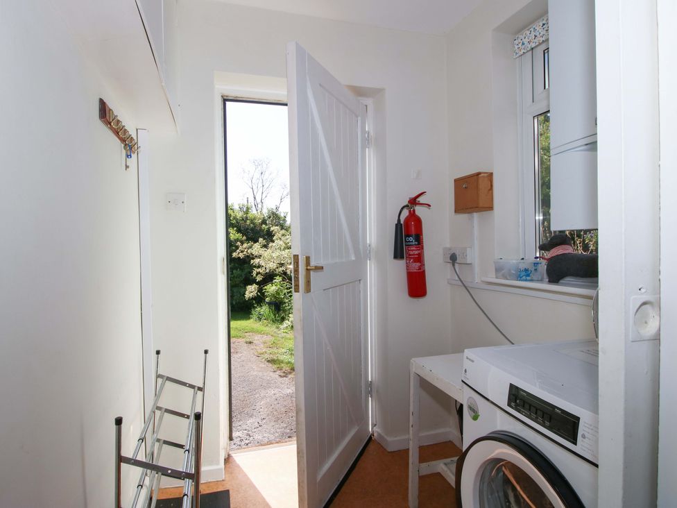 A utility room with a washing machine and a door leading outside at Shepherd's Cottage Eudon Burnell near Bridgnorth