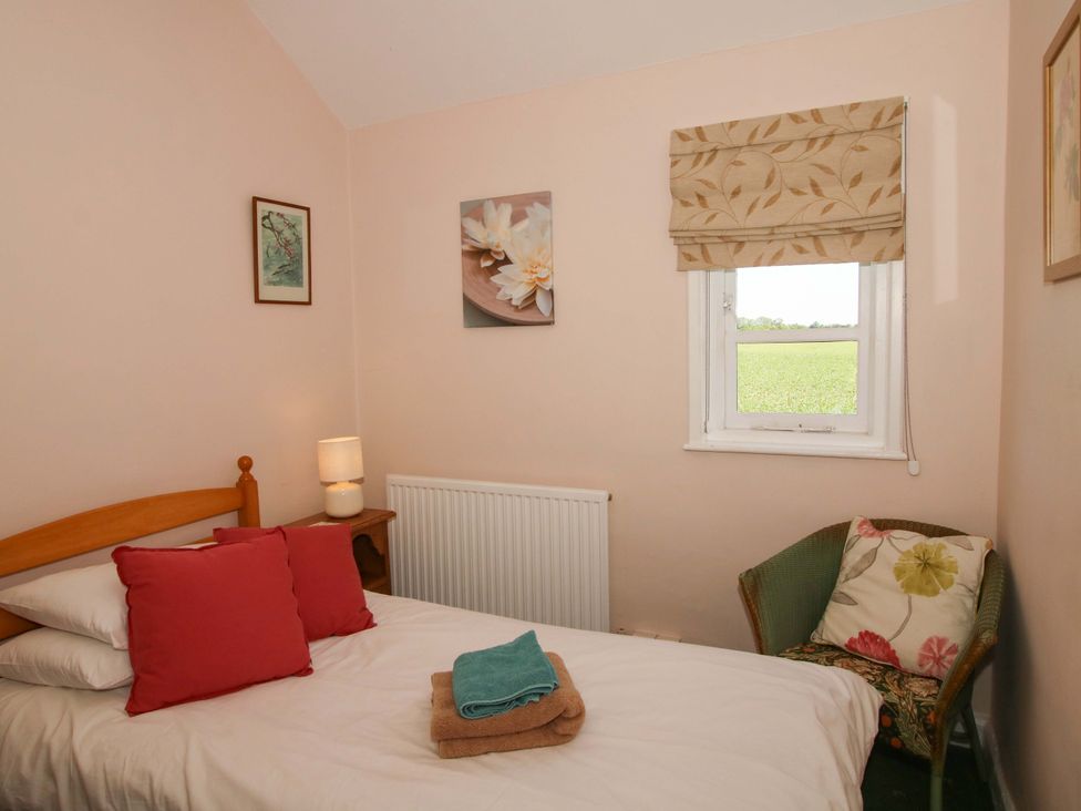 A bedroom with a bed and a chair at Shepherd's Cottage in Eudon Burnell near Bridgnorth