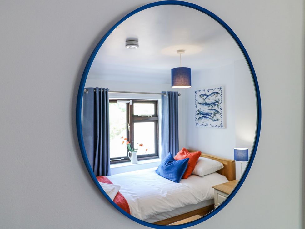 A bedroom with a bed with blue and red pillows and blue curtains at Corner Cottage in Ashbourne