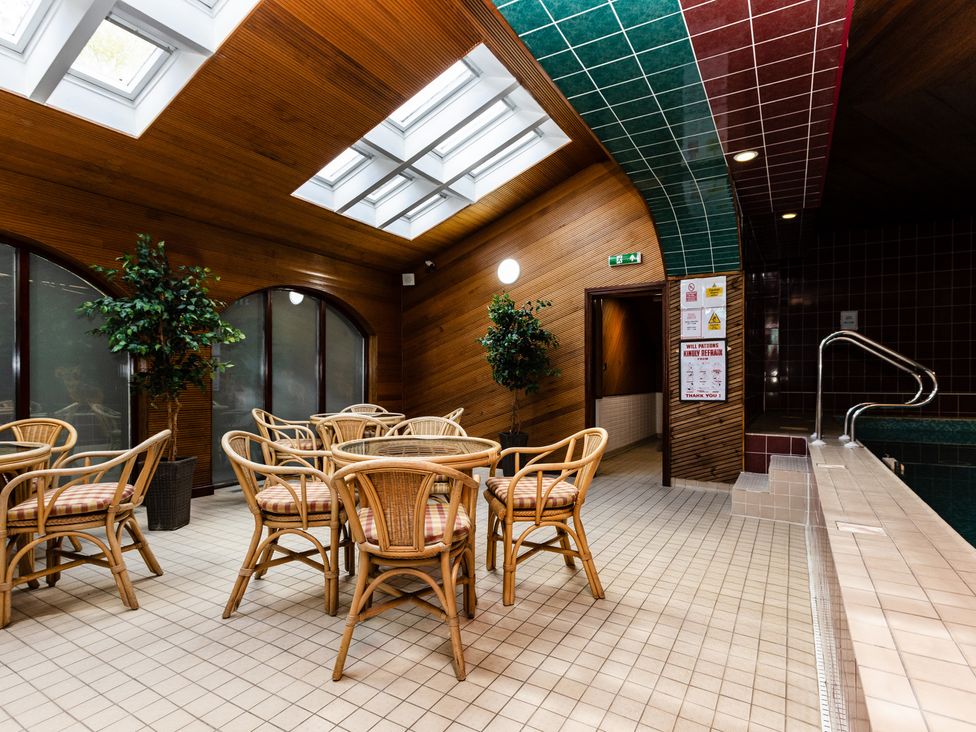 An indoor pool area with seating and tables at Primula Patch Akeld near Wooler