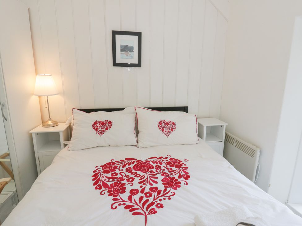 A bedroom featuring a bed with decorative pillows and a lamp at Brynmorfa in Llandysul