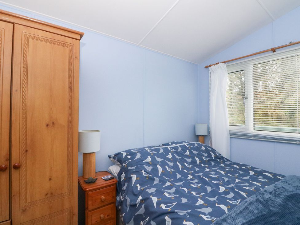 A bedroom with a bed, wardrobe, lamp, and window at Scarba in Oban