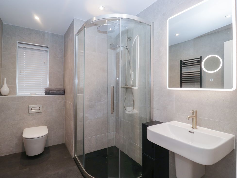 A bathroom with a shower, toilet, and sink at Cross Winds in Clapham