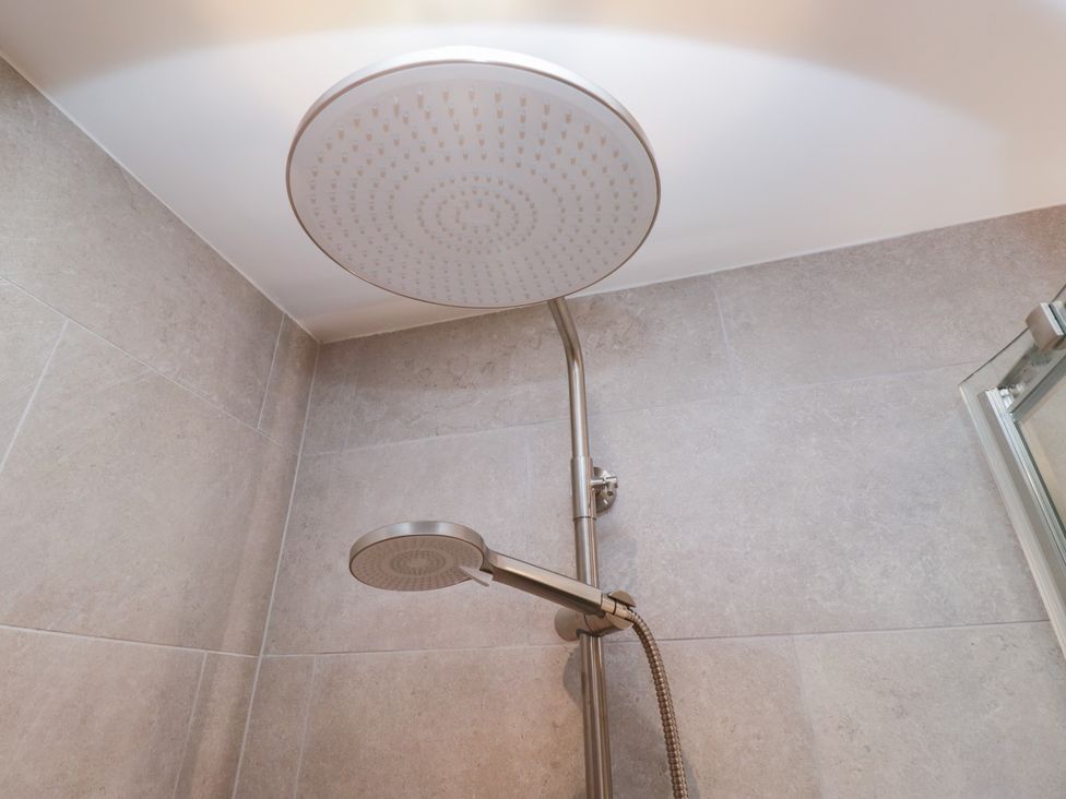 A shower head with an arm in a bathroom at Cross Winds in Clapham