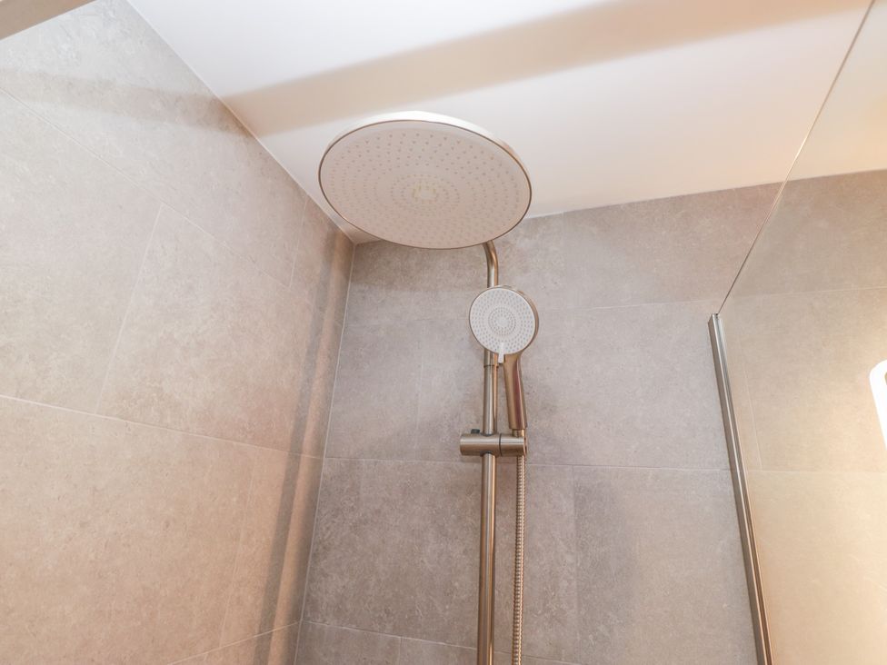 A shower with a ceiling shower head and hand shower at Cross Winds in Clapham