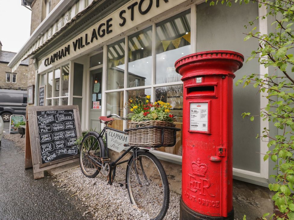An outdoor scene with a bicycle, post box and signboard at Clapham Village Store in Clapham