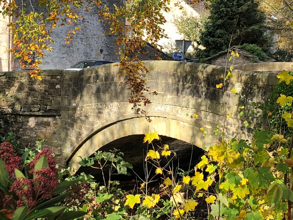 A stone bridge over a stream with plants and a car at Cross Winds in Clapham