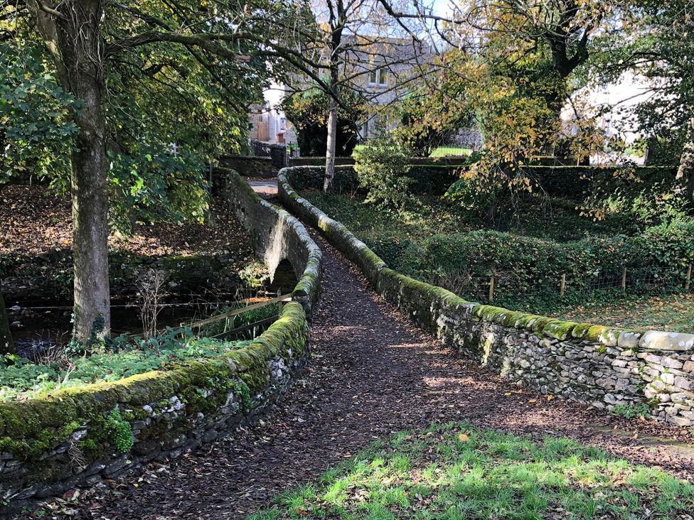 A path alongside a stone wall and trees at Cross Winds in Clapham