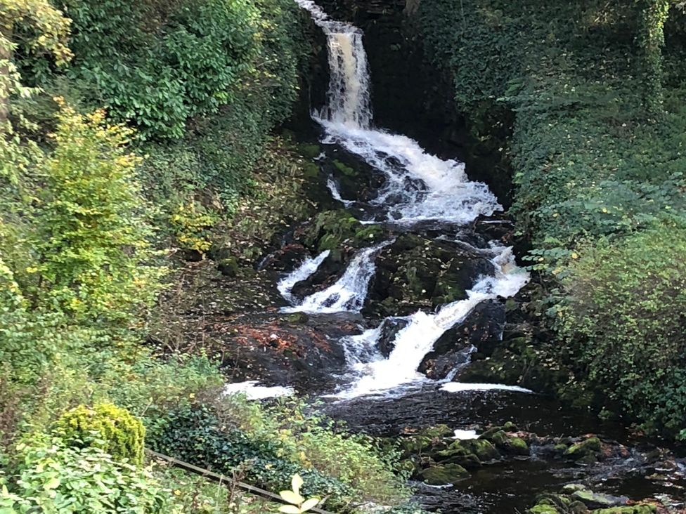 A waterfall cascading over rocks surrounded by greenery at Cross Winds in Clapham