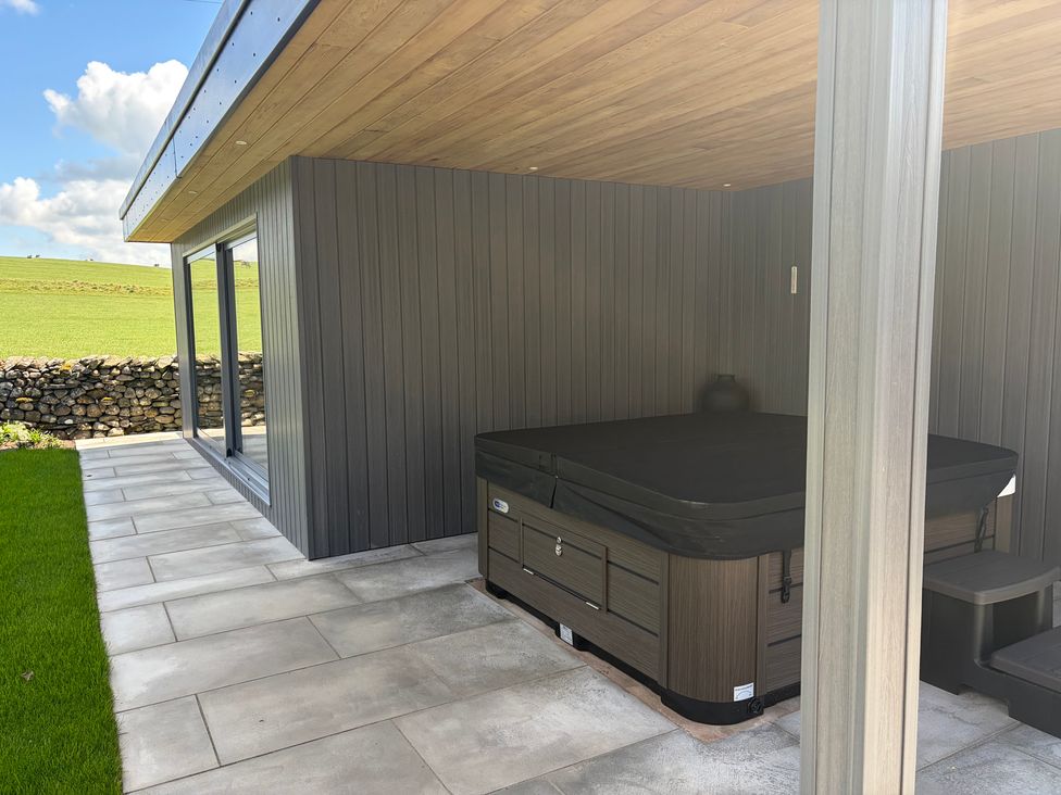 An outdoor area with a hot tub and sliding glass door at Cross Winds in Clapham