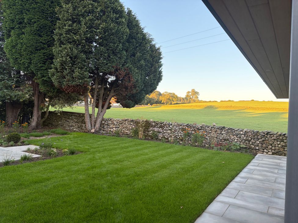A garden with trees and a stone wall at Cross Winds in Clapham