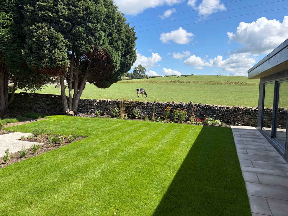 A garden with grass and a stone wall at Cross Winds in Clapham
