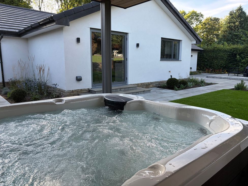 A hot tub with a view of a house and garden at Cross Winds in Clapham