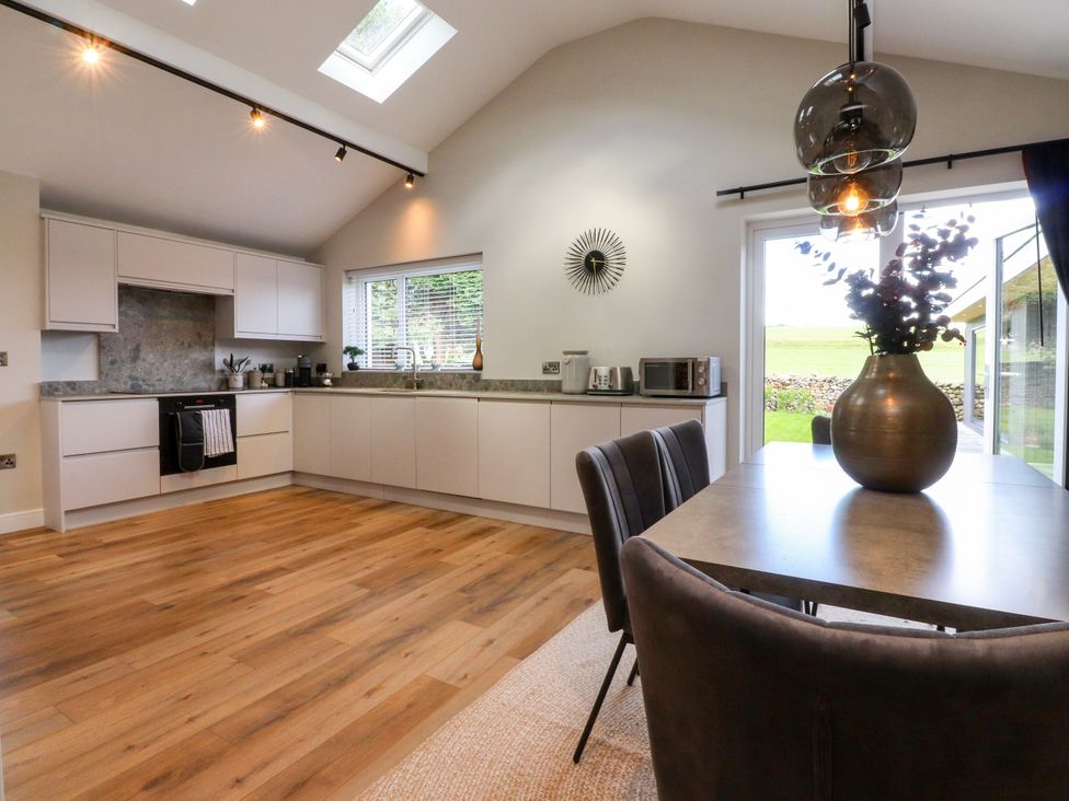 A kitchen with a dining table and modern appliances at Cross Winds in Clapham