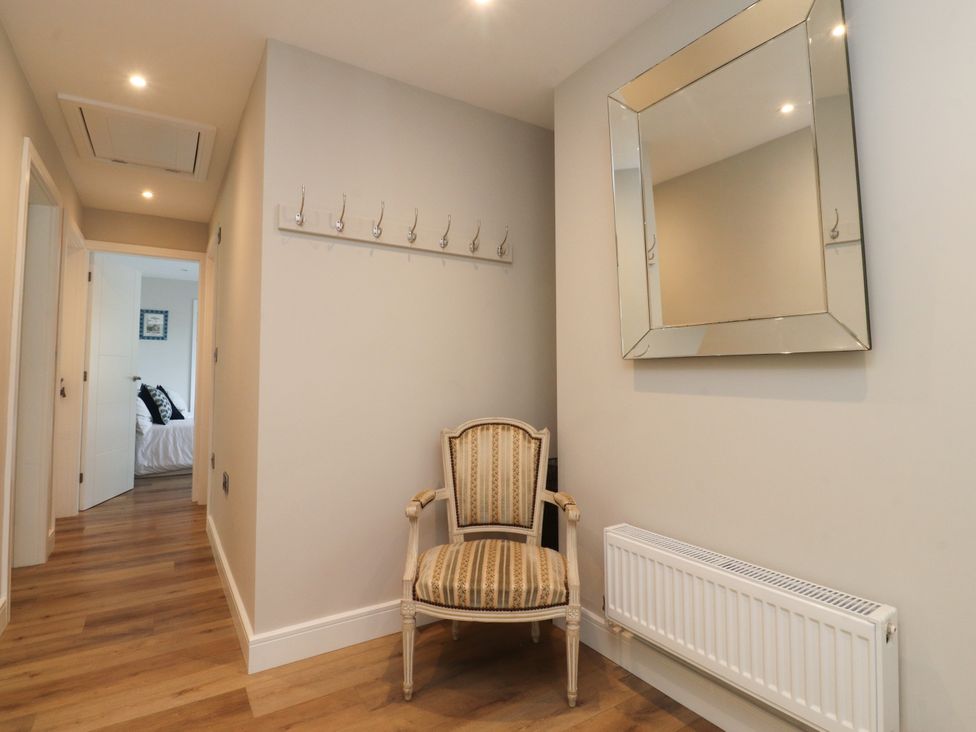 A hallway with a chair and coat hooks at Cross Winds in Clapham