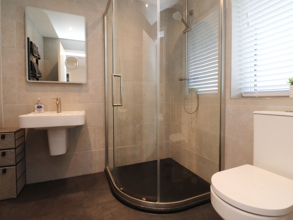 A bathroom with a shower, sink, and toilet at Cross Winds in Clapham