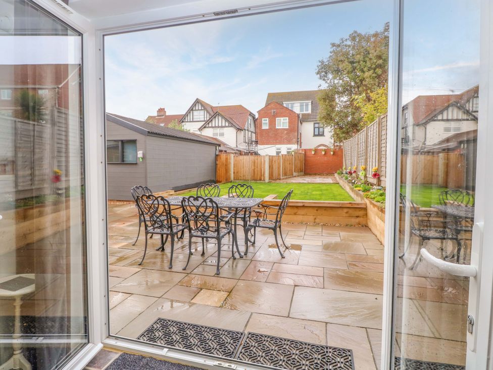 A garden with a patio area and a dining table at Highland House in Sheringham