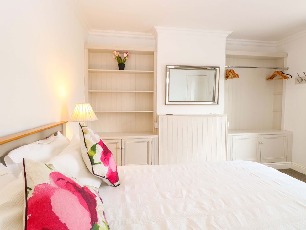 A bedroom with a bed and shelves at Highland House Sheringham