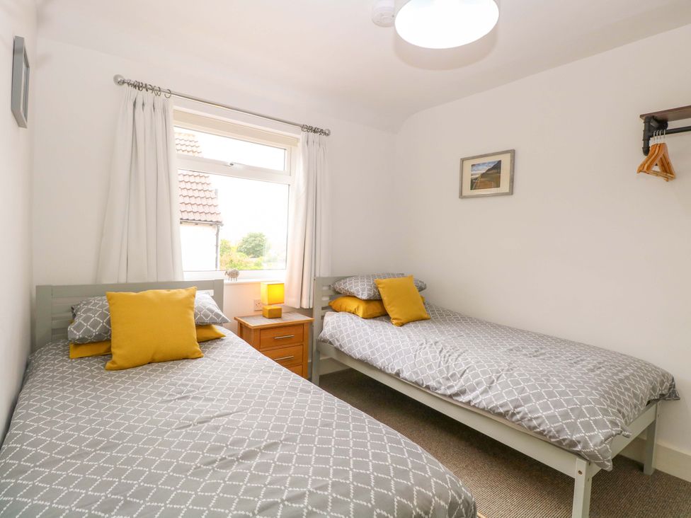 A bedroom with two beds and a nightstand at Highland House in Sheringham