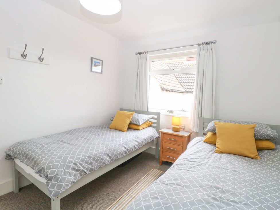 A bedroom with twin beds and a nightstand at Highland House in Sheringham