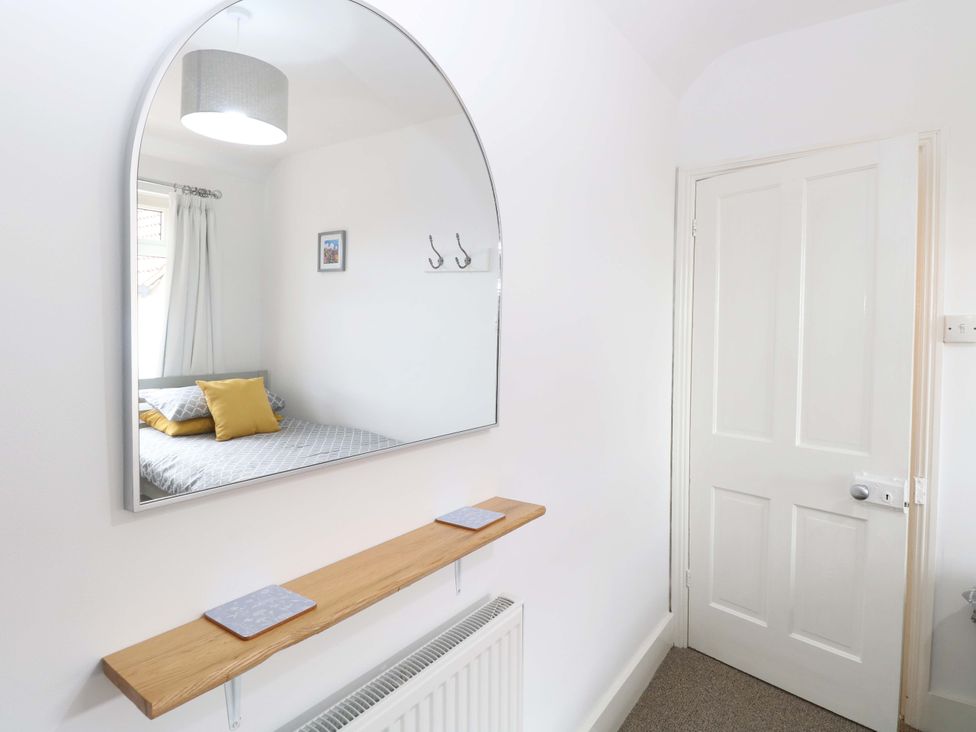 A bedroom with a mirror and shelf at Highland House in Sheringham