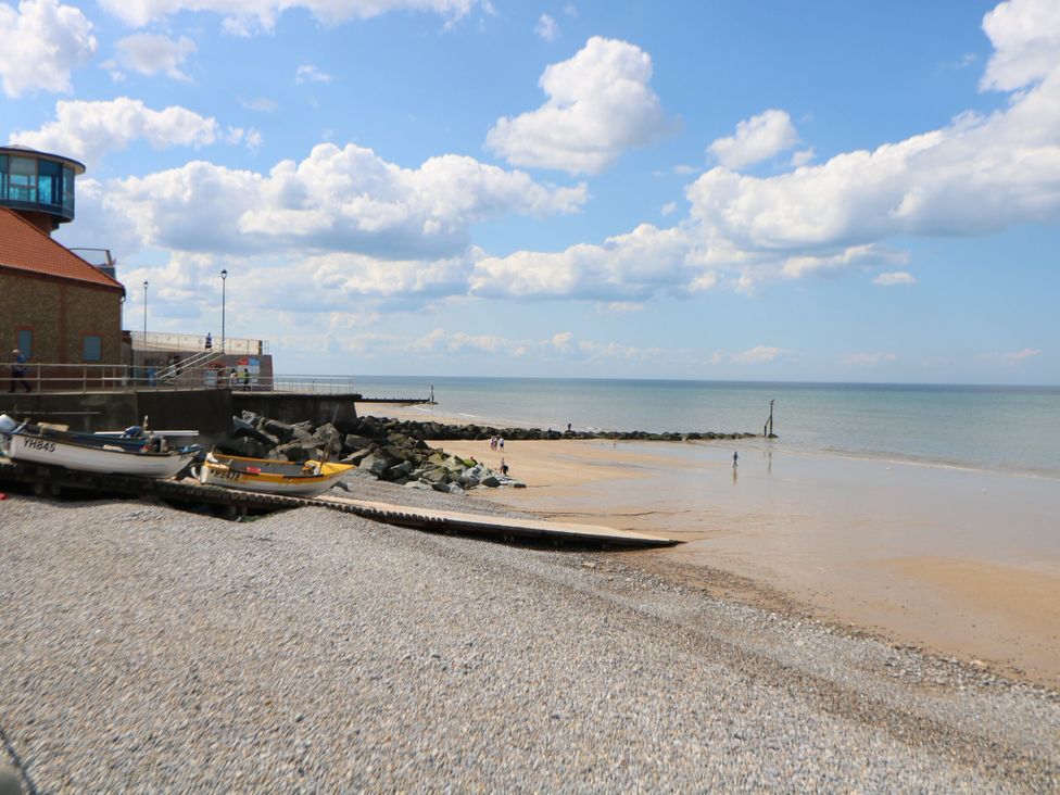 A beach with boats and a building at Highland House in Sheringham