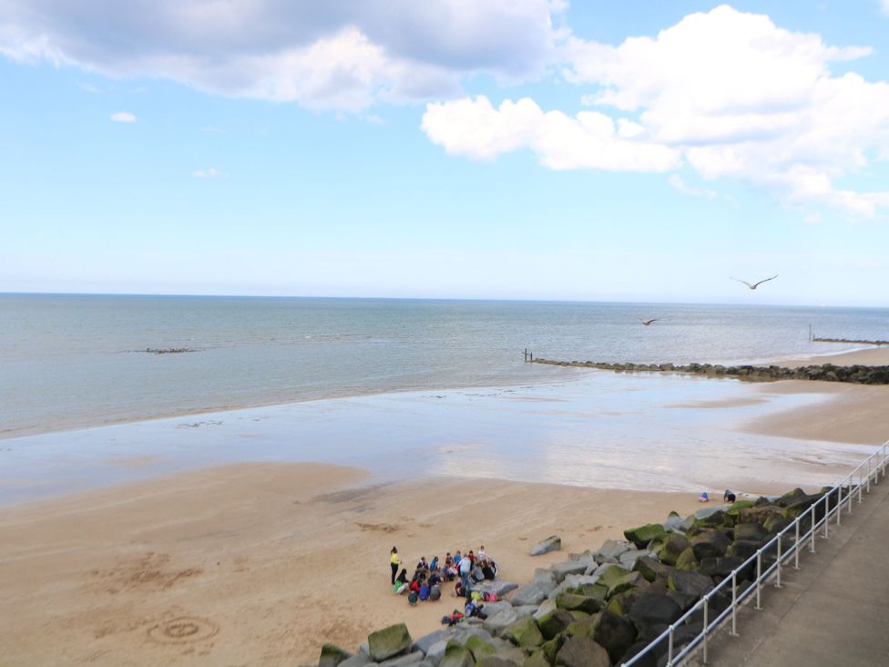 A beach scene with people gathered on the sand at Highland House in Sheringham
