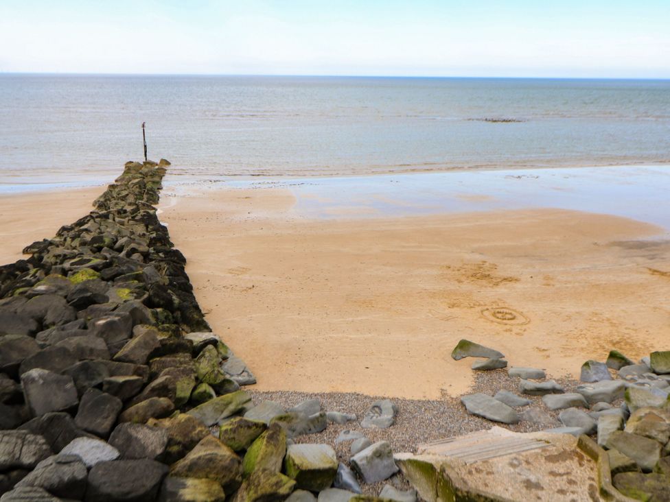 A beach with a rock pier and ocean at Highland House Sheringham