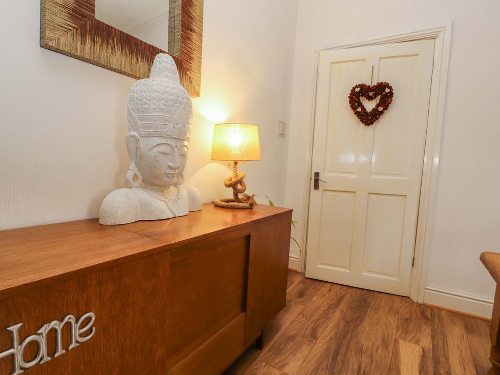 An entryway with a wooden cabinet, bust sculpture, lamp, and door at 2 The Crescent