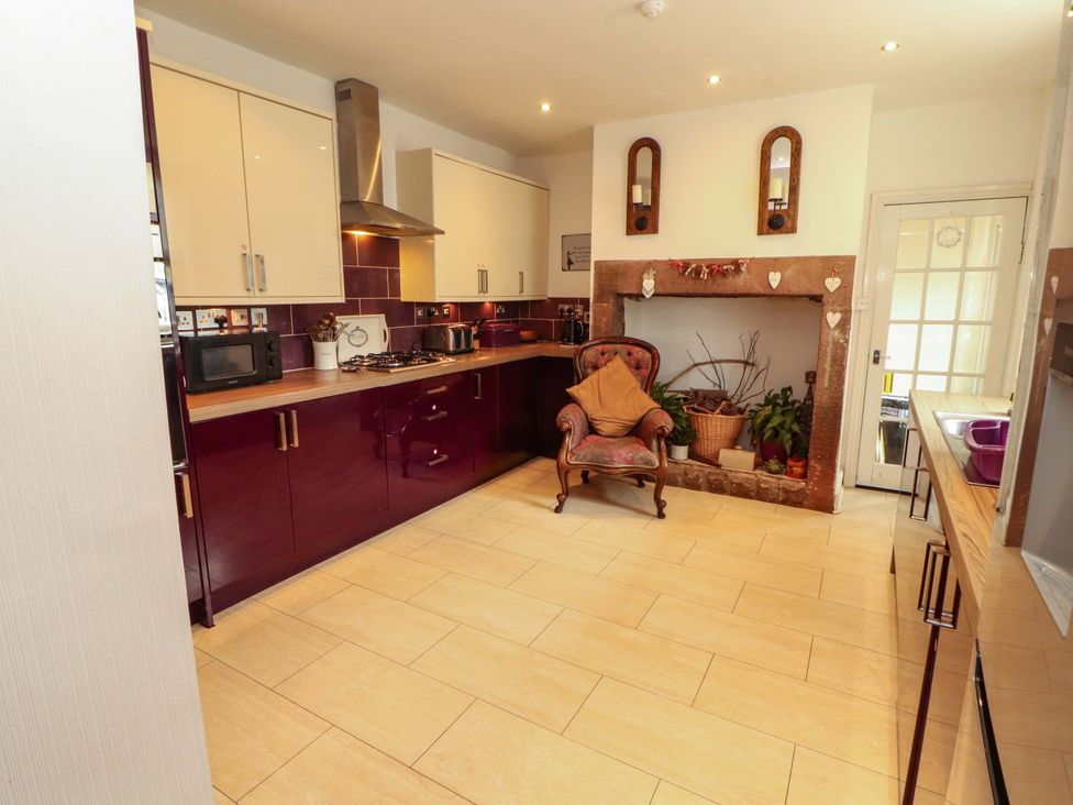A kitchen with cabinets, a chair, and a cooking range at 2 The Crescent