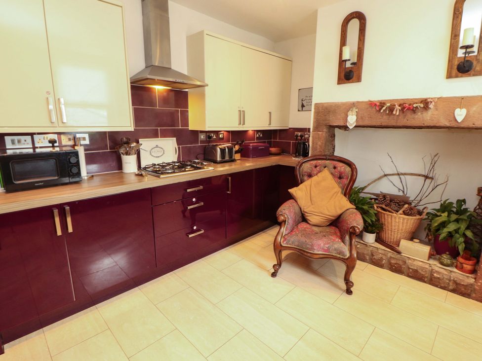 A kitchen with cabinets, stove, and a chair at 2 The Crescent