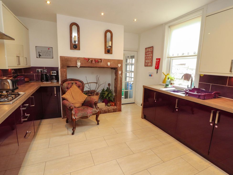 A kitchen with a stove, sink, and chair at 2 The Crescent