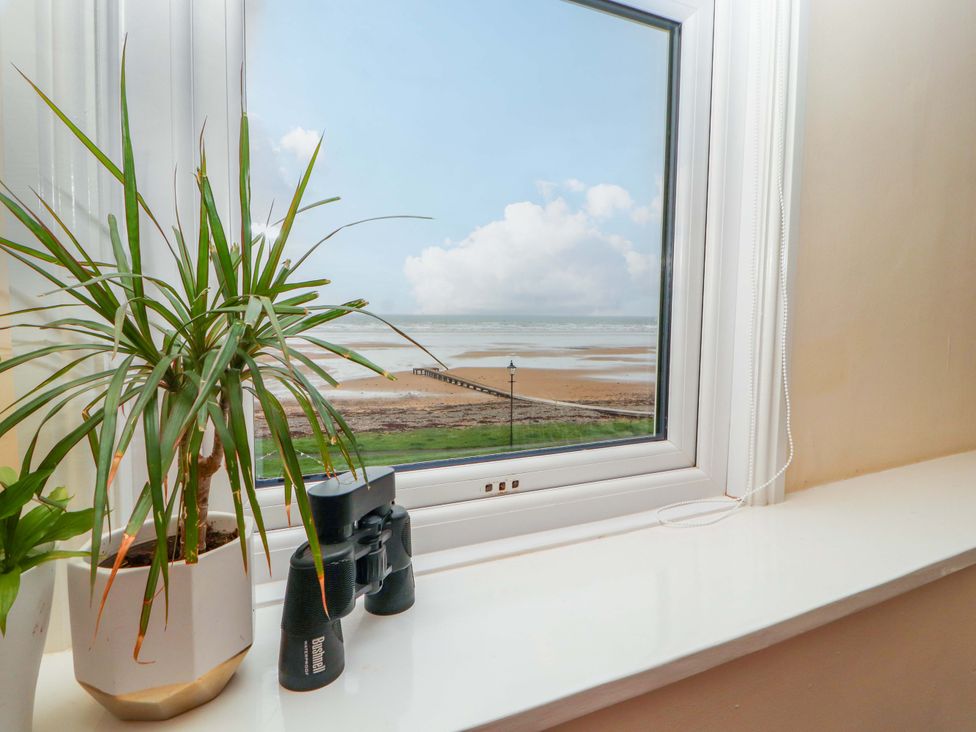 A window with a view of the sea and binoculars on the ledge at 2 The Crescent