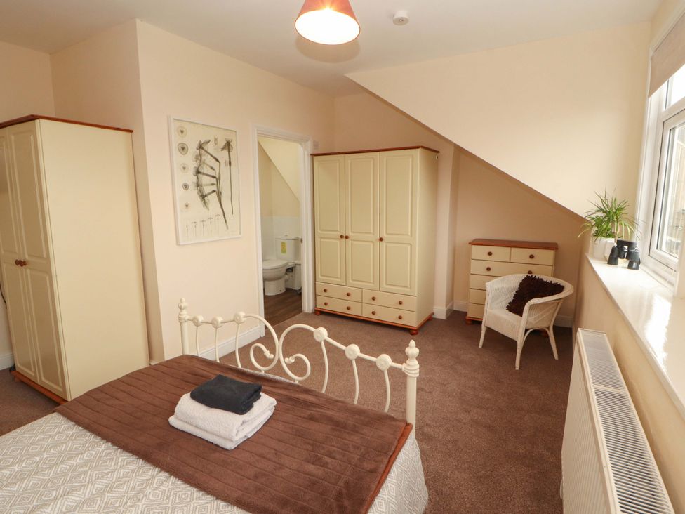 A bedroom with a bed, wardrobe, and a chair at 2 The Crescent