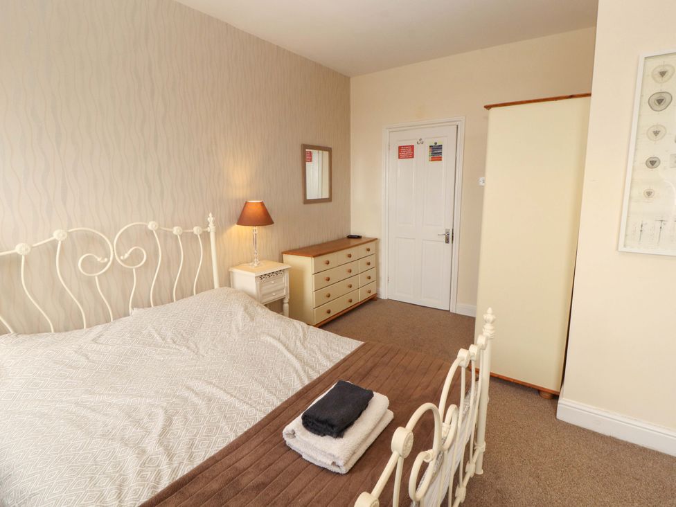 A bedroom with a bed, lamp, dresser, and wardrobe at 2 The Crescent