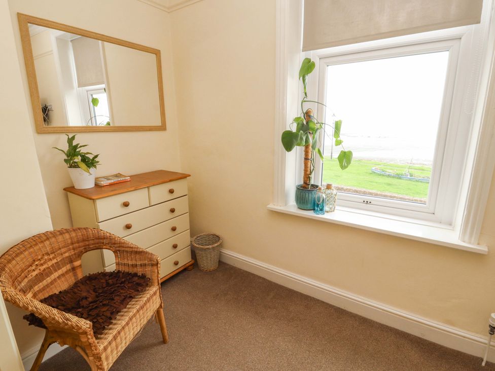A room with a chair, dresser, mirror, and plant at 2 The Crescent