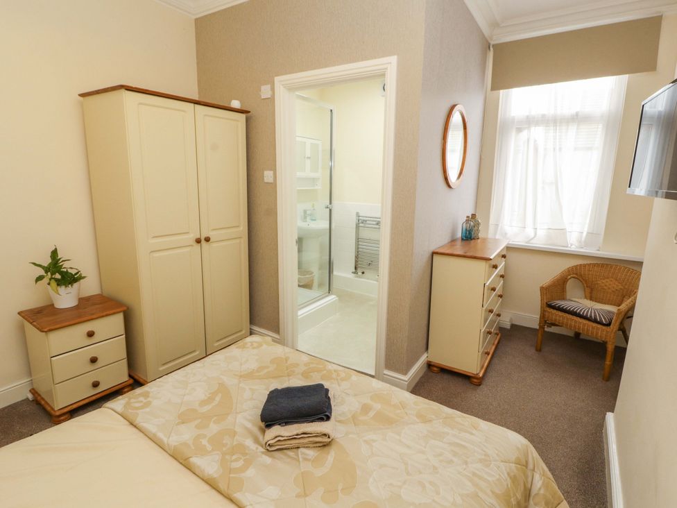 A bedroom with a bed, wardrobe, chest of drawers, and a shower at 2 The Crescent