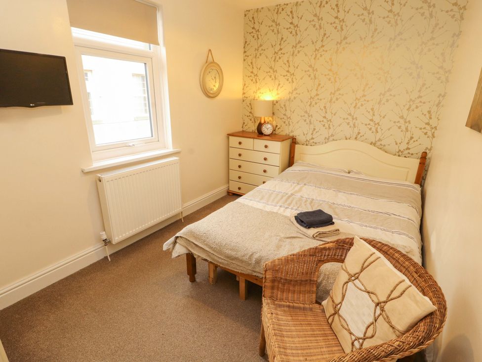A bedroom with a bed, chair, television, and window at 2 The Crescent