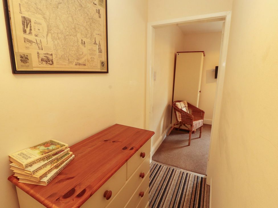 A hallway with a chest of drawers and a wicker chair at 2 The Crescent