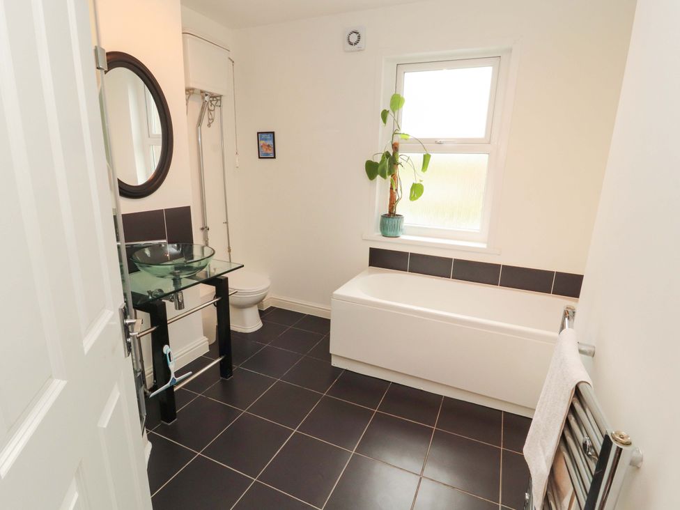 A bathroom with a sink, toilet, bath tube and a plant at 2 The Crescent