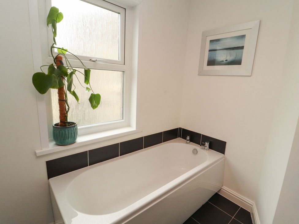 A bathroom with a bathtub and a plant on the windowsill at 2 The Crescent