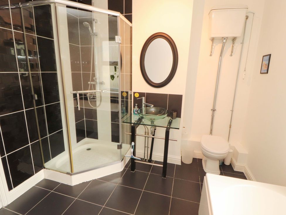 A bathroom with a shower, toilet, and glass wash basin at 2 The Crescent 