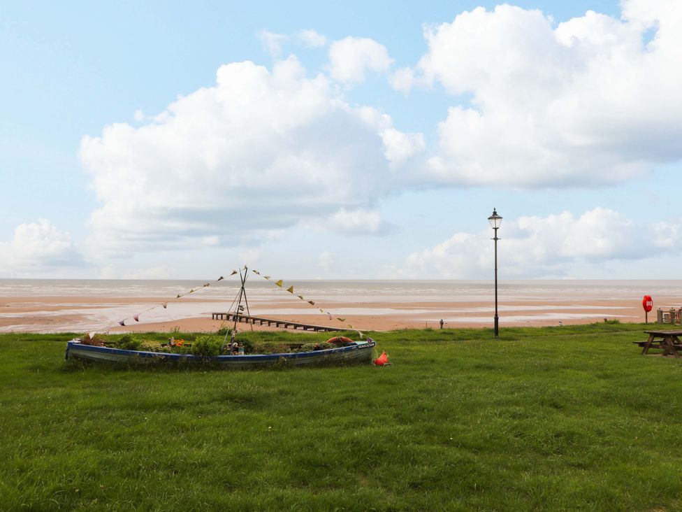 A beach scene with a boat, lamp post, and pier at 2 The Crescent in 