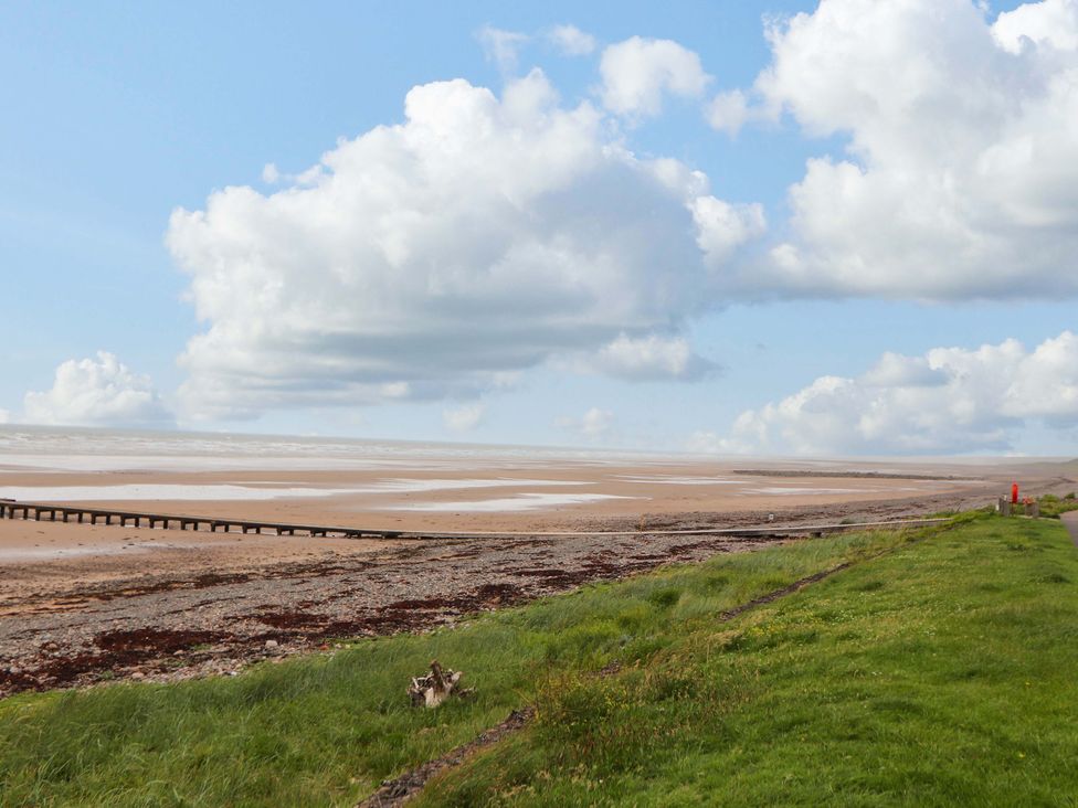 A beach with a pier and grass along the shoreline at 2 The Crescent 