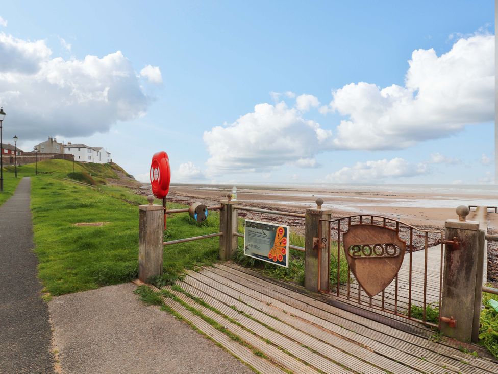 A view of a pathway leading to a beach with a life buoy at 2 The Crescent