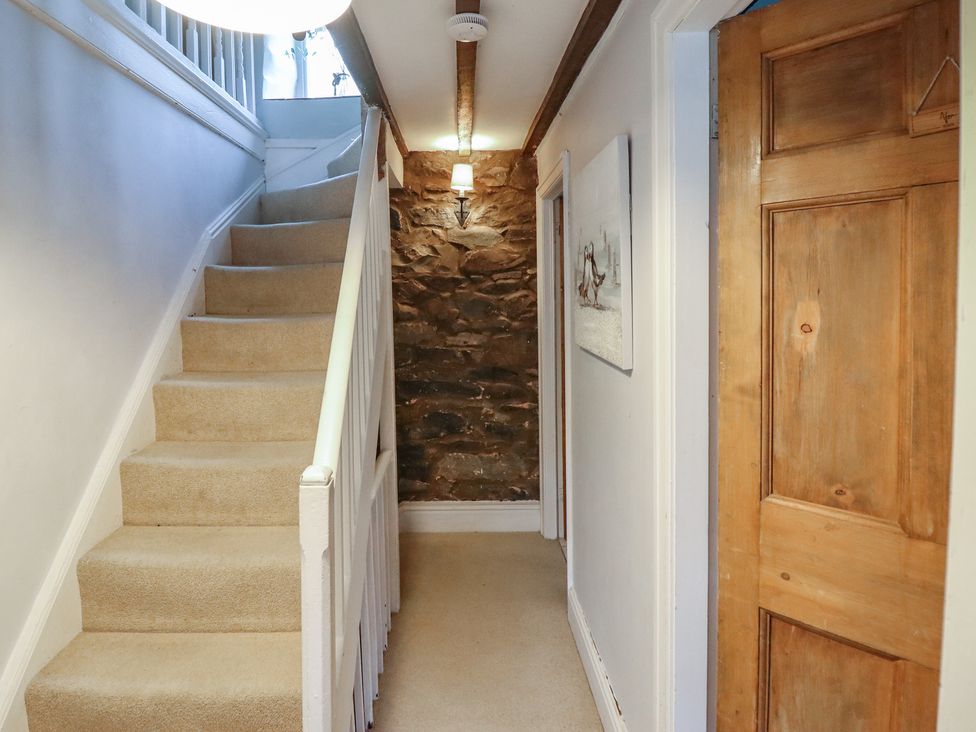 A hallway with stairs and a stone wall at Riverwash Cottage in Dwygyfylchi