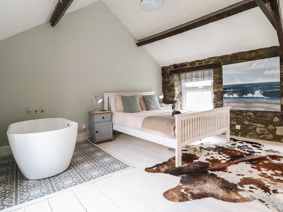 A bedroom with a bed and bathtub at Riverwash Cottage in Dwygyfylchi