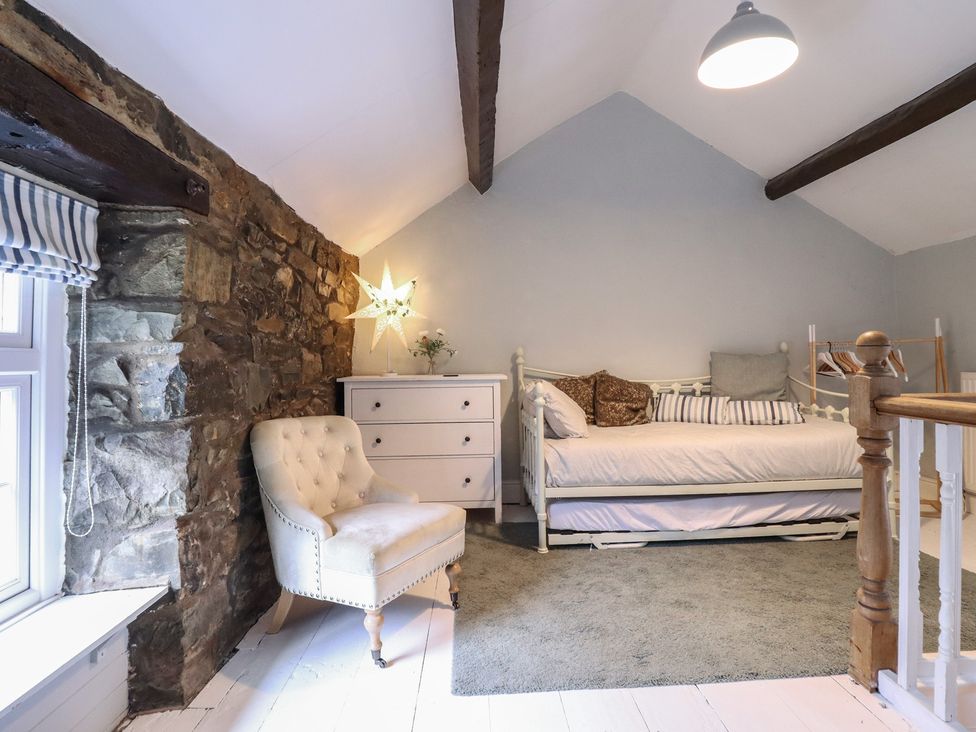 A bedroom featuring a bed and chair at Riverwash Cottage in Dwygyfylchi